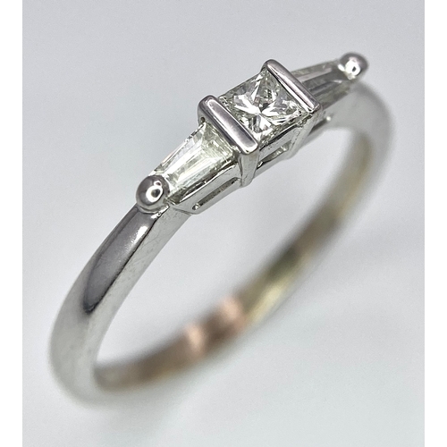 802 - AN 18K WHITE GOLD, DIAMOND 3 STONE RING - PRINCESS CUT CENTRE WITH A TAPPERED BAGUETTE DIAMOND EITHE... 