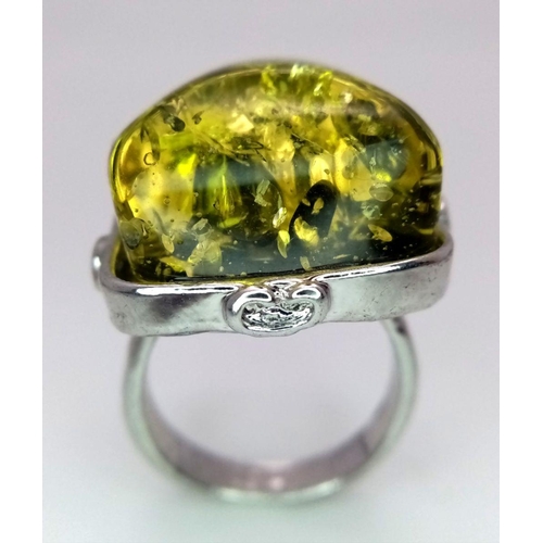 1446 - A white metal (untested) ring with a large yellow-green amber resin cabochon, size: T, weight: 12 g