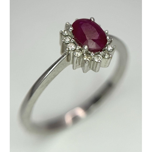 176 - An 18K White Gold Ruby and Diamond Ring. Central oval cut ruby with a diamond halo. Size N. 2.7g tot... 