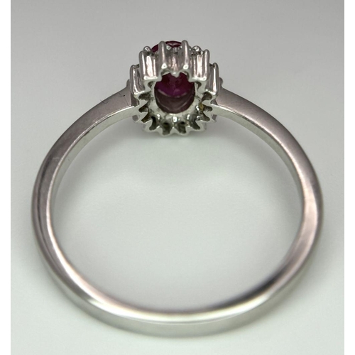 176 - An 18K White Gold Ruby and Diamond Ring. Central oval cut ruby with a diamond halo. Size N. 2.7g tot... 