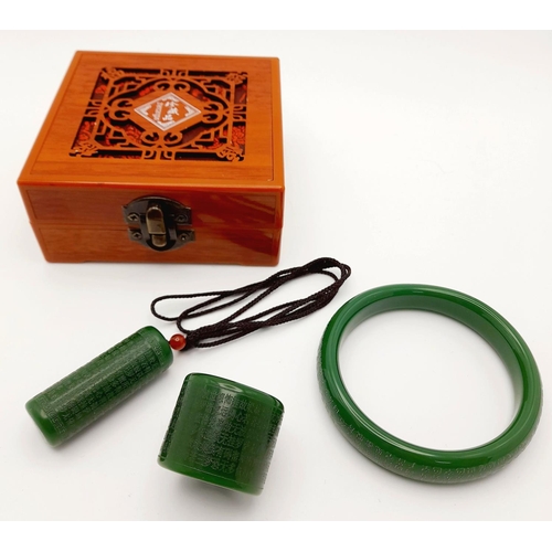 160 - Of Buddhist interest: A green jade set consisting of a bangle, a thumb ring and a pendant/amulet wit... 