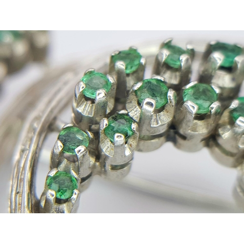 200 - A Beautiful 18K White Gold Emerald and Diamond Swirling Brooch. 1.5ctw of round cut emeralds and 1ct... 