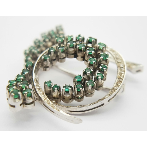 200 - A Beautiful 18K White Gold Emerald and Diamond Swirling Brooch. 1.5ctw of round cut emeralds and 1ct... 