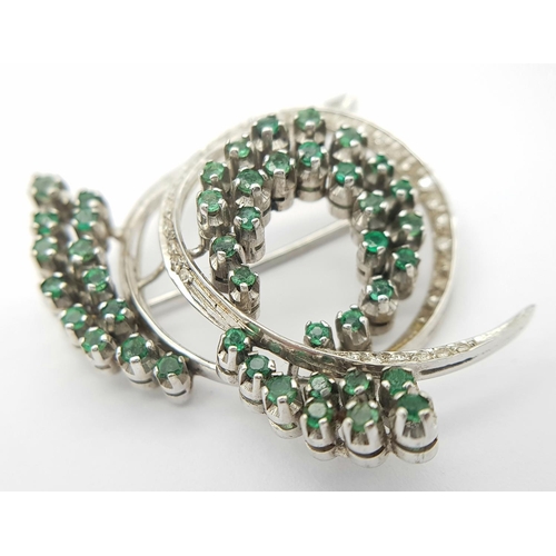 200 - A Beautiful 18K White Gold Emerald and Diamond Swirling Brooch. 1.5ctw of round cut emeralds and 1ct... 