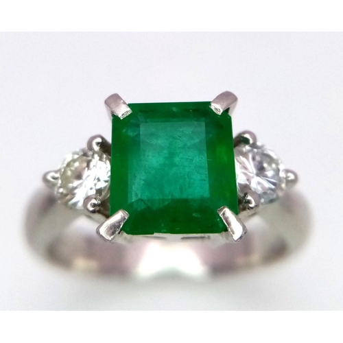 149 - A 900 Platinum Emerald and Diamond Ring. Central emerald with a 0.20 brilliant round cut diamond eit... 