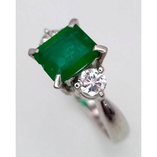 149 - A 900 Platinum Emerald and Diamond Ring. Central emerald with a 0.20 brilliant round cut diamond eit... 