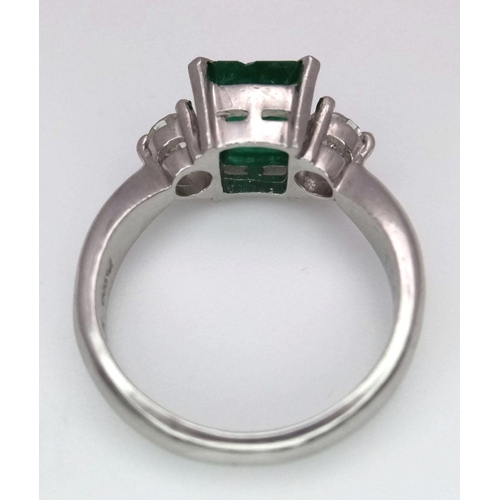 149 - A 900 Platinum Emerald and Diamond Ring. Central emerald with a 0.20 brilliant round cut diamond eit... 