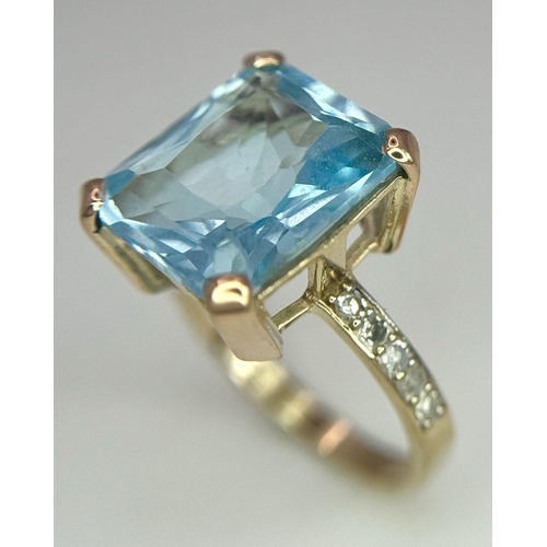 387 - A 9K Yellow Gold Blue Topaz and Diamond Ring. Central topaz with diamond accents. Size O. 3.9g total... 