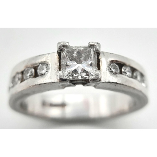 100 - A 950 Platinum Diamond Ring. A 0.30ct princess cut central diamond with five round cut diamonds on e... 