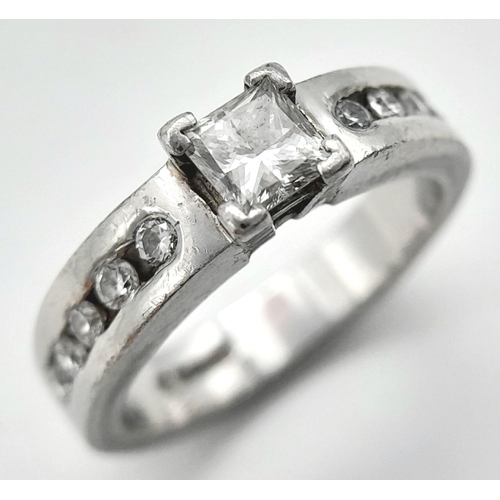 100 - A 950 Platinum Diamond Ring. A 0.30ct princess cut central diamond with five round cut diamonds on e... 