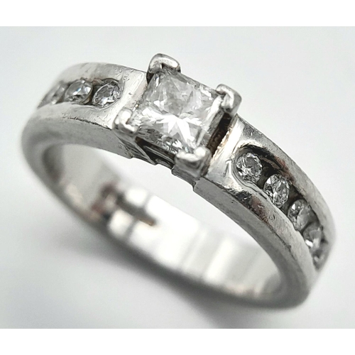 100 - A 950 Platinum Diamond Ring. A 0.30ct princess cut central diamond with five round cut diamonds on e... 