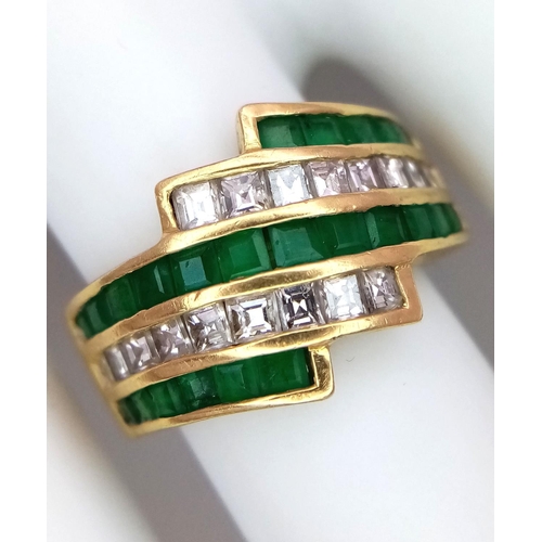 85 - An 18K Yellow Gold Emerald and Diamond Swirl Ring. 0.6ctw emeralds, 0.5ctw diamonds approx. Size K. ... 