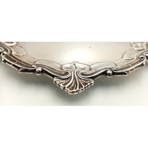 268 - A SOLID SILVER FOOTED PLATTER HALLMARKED LONDON 1932 WITH INTRICATE SCROLLED EDGING.   183.5gms    1... 