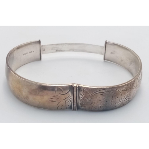 365 - A VINTAGE SOLID SILVER HINGED BANGLE WITH ATTRACTIVE DECORATION TO ONE SIDE .   35gms