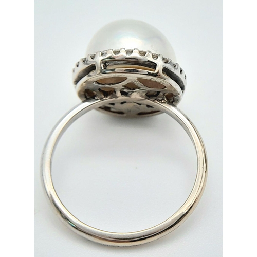 421 - An 18K White Gold South Sea Pearl and Diamond Ring. A South Sea Pearl Cabochon with diamond halo. Si... 