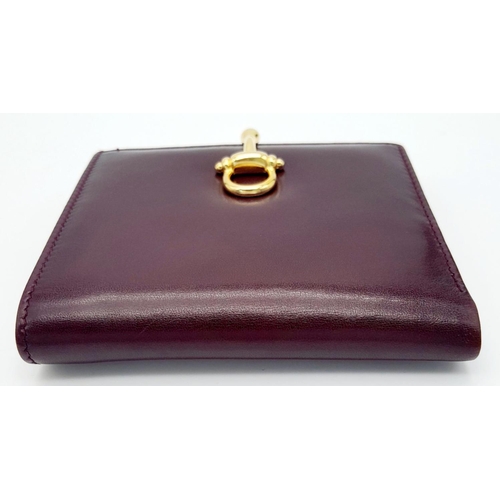 1404 - A Launer Burgundy Wallet. Leather exterior, gold-tone metal clasp that open to reveal six card slots... 