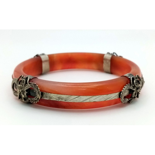 192 - An antique, Chinese, red-brown jade bangle with white metal ornaments, representing protective drago... 