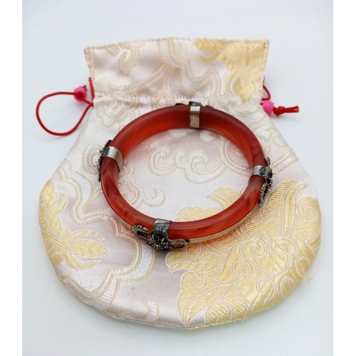 192 - An antique, Chinese, red-brown jade bangle with white metal ornaments, representing protective drago... 