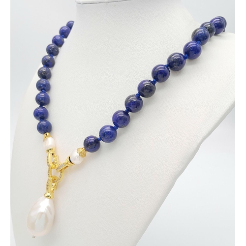 241 - A Lapis Lazuli Beaded Necklace with a Hanging Baroque Pearl Pendant. Gilded clasp with white stone a... 