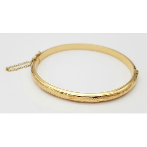 248 - A 9K Yellow Gold Bangle. Clip design with safety chain. 6cm inner diameter. 8.25g.