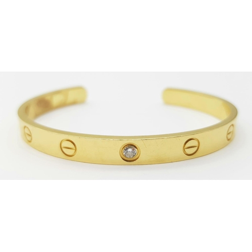 11 - A Cartier 18K Yellow Gold and Solitary Diamond Cuff Bangle. Classic Cartier design with full Maker/H... 