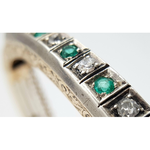 102 - A 9K Gold Emerald and Diamond Set Bangle. Clip design with safety chain. Alternating diamonds and em... 