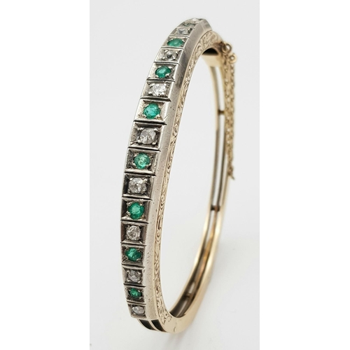 102 - A 9K Gold Emerald and Diamond Set Bangle. Clip design with safety chain. Alternating diamonds and em... 