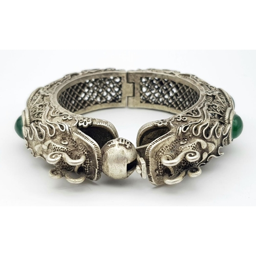 450 - A Tibetan Silver Double Dragon Statement Bracelet with Green Jade Cabochon Decoration. Tells the sto... 