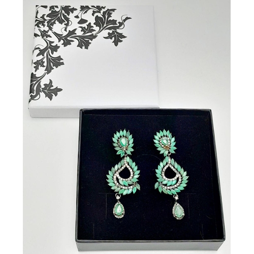 112 - An vintage sterling silver pair of earrings with old cut diamonds and oval cut emeralds. In excellen... 