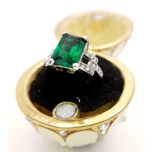 238 - A fabulous dress ring presented in a Faberge style egg resting on an elaborate base. Ring size: O