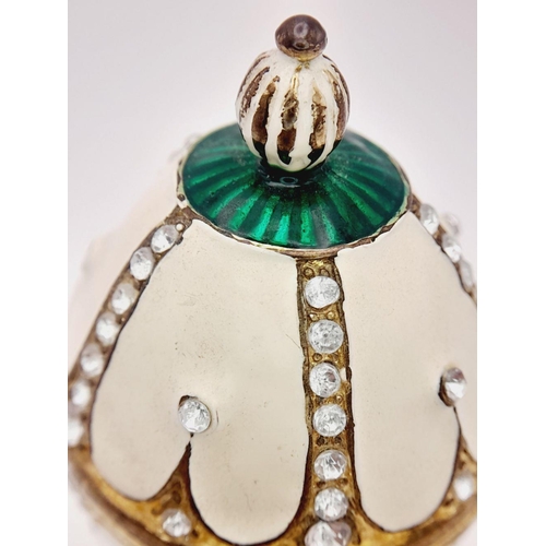 238 - A fabulous dress ring presented in a Faberge style egg resting on an elaborate base. Ring size: O