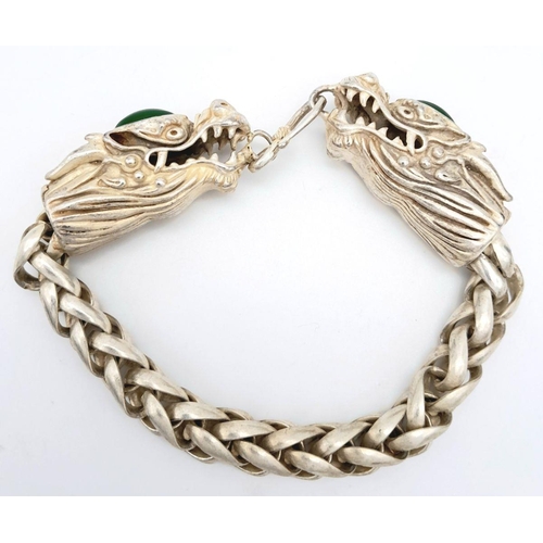 393 - A Tibetan Silver Double-Headed-Dragon Bracelet. Green Jade cabochon decoration. 20cm length.