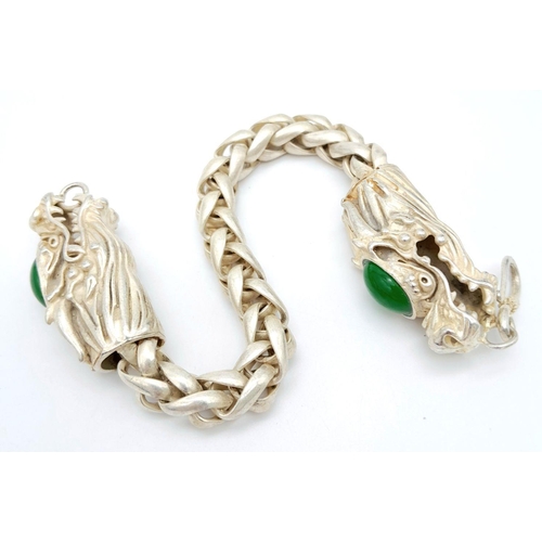 393 - A Tibetan Silver Double-Headed-Dragon Bracelet. Green Jade cabochon decoration. 20cm length.