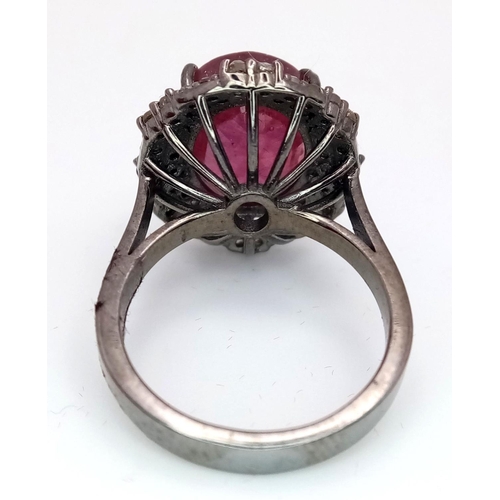 141 - A 6.35ct Oval Cut Ruby Ring with a 0.75ctw Diamond Surround - Set in 925 Silver. Size L. Comes with ... 