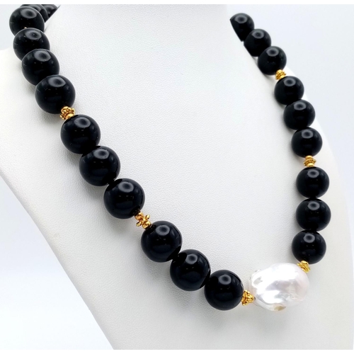 369 - A Mesmerising Black Onyx Beaded Necklace with White Baroque Pearl Interrupter. Gilded spacers and cl... 