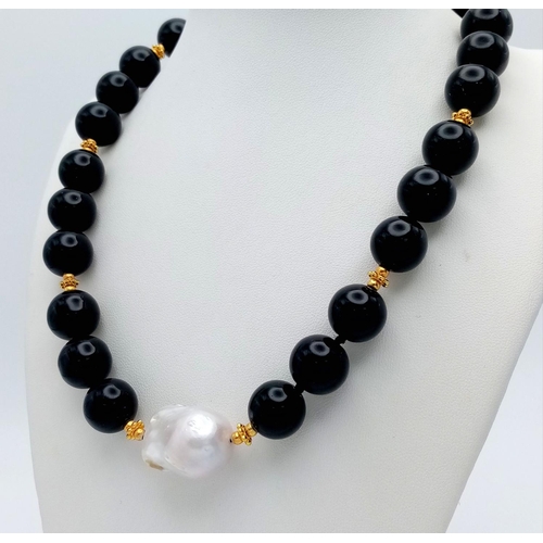 369 - A Mesmerising Black Onyx Beaded Necklace with White Baroque Pearl Interrupter. Gilded spacers and cl... 