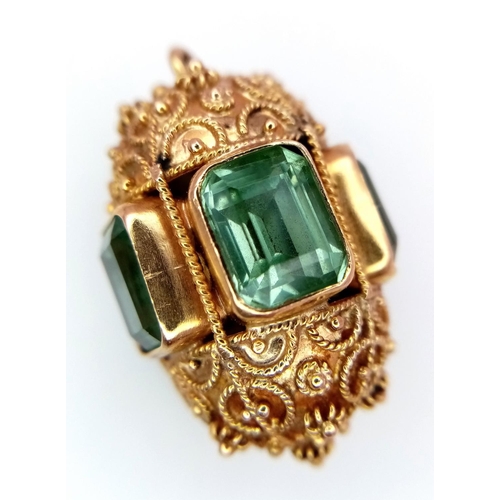 53 - An 18K Yellow Ornate Emerald Egg-Shaped Pendant. Five rectangular cut emeralds. Tests as 18k gold. 3... 