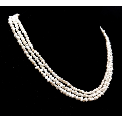 856 - A Three Row Petit Rice Pearl Necklace with 9k Gold Clasp. 40cm.