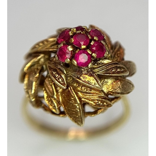 78 - An 18K Yellow Gold (tested) and Ruby Ring in Floral Form. Seven round cut rubies amidst leaves of 18... 