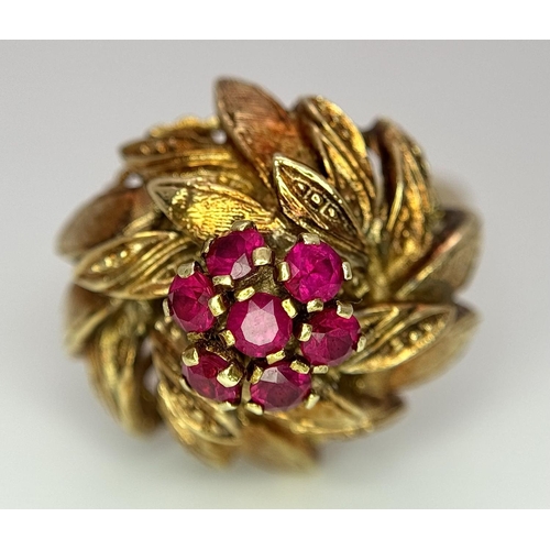 78 - An 18K Yellow Gold (tested) and Ruby Ring in Floral Form. Seven round cut rubies amidst leaves of 18... 