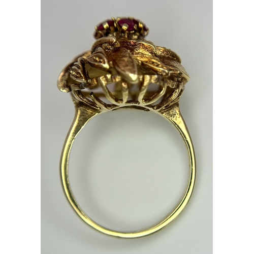 78 - An 18K Yellow Gold (tested) and Ruby Ring in Floral Form. Seven round cut rubies amidst leaves of 18... 