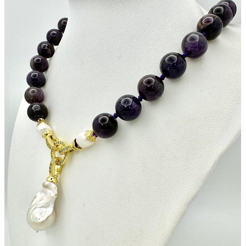 316 - A Deep Purple Amethyst Bead Necklace with a Baroque Pearl Drop Pendant. 12mm amethyst beads. Gilded,... 