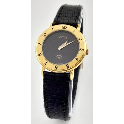 1156 - A Classic Gucci Gold Plated Ladies Quartz Watch. Black leather strap. Gilded case - 26mm. Black dial... 