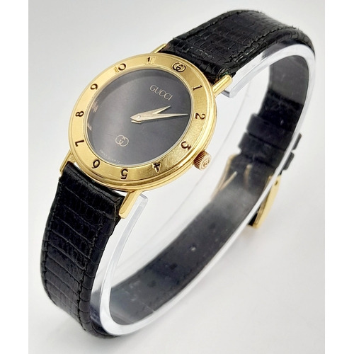 1156 - A Classic Gucci Gold Plated Ladies Quartz Watch. Black leather strap. Gilded case - 26mm. Black dial... 