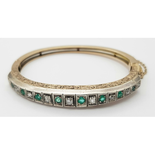 1089 - A 9K Gold Emerald and Diamond Set Bangle. Clip design with safety chain. Alternating diamonds and em... 