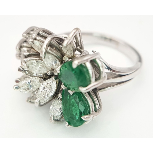 33 - An 18 K white gold ring with two rear cut emeralds counterbalanced  by a cluster of marquise cut dia... 