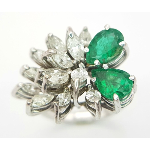 33 - An 18 K white gold ring with two rear cut emeralds counterbalanced  by a cluster of marquise cut dia... 