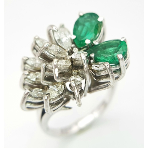 33 - An 18 K white gold ring with two rear cut emeralds counterbalanced  by a cluster of marquise cut dia... 