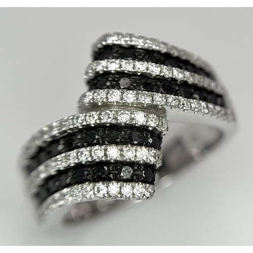 502 - A 14K WHITE GOLD WHITE & BLACK DIAMOND CROSSOVER RING. 1.25CT. 7.8G IN WEIGHT. SIZE N AND 1/2. Ref: ... 