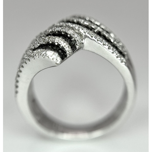 502 - A 14K WHITE GOLD WHITE & BLACK DIAMOND CROSSOVER RING. 1.25CT. 7.8G IN WEIGHT. SIZE N AND 1/2. Ref: ... 